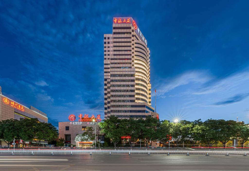 un grand bâtiment avec un panneau rouge en haut dans l'établissement Baoding Zhong Yin Hotel, à Baoding