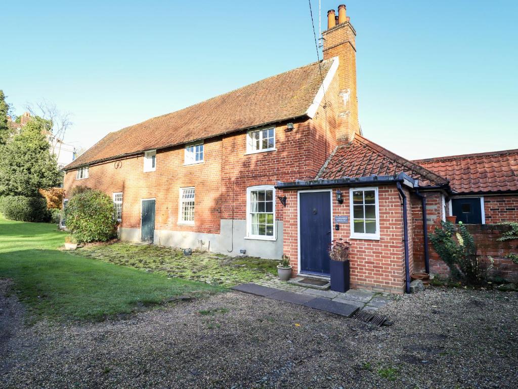 uma casa de tijolos com uma porta azul e um quintal em Gardener's Cottage em Hadleigh