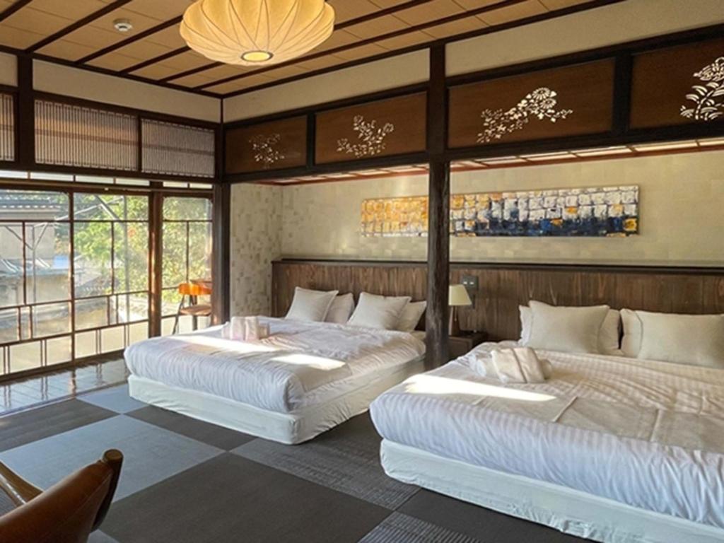 two beds in a room with windows at KIYOMORI in Hatsukaichi