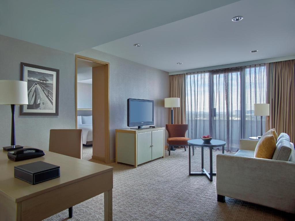 a living room filled with furniture and a large window at New World Makati Hotel, Manila in Manila