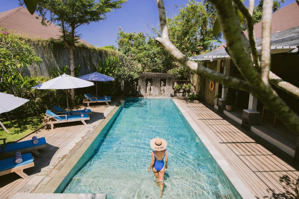 a woman in a hat in a swimming pool at La Berceuse Resort and Villa Nusa Dua by Taritiya Collection in Nusa Dua