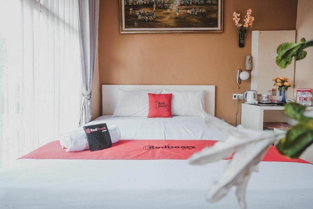 um quarto com uma cama branca e almofadas vermelhas em Koolkost Syariah near Plaza Ambarukmo - Minimum Stay 30 Nights em Yogyakarta