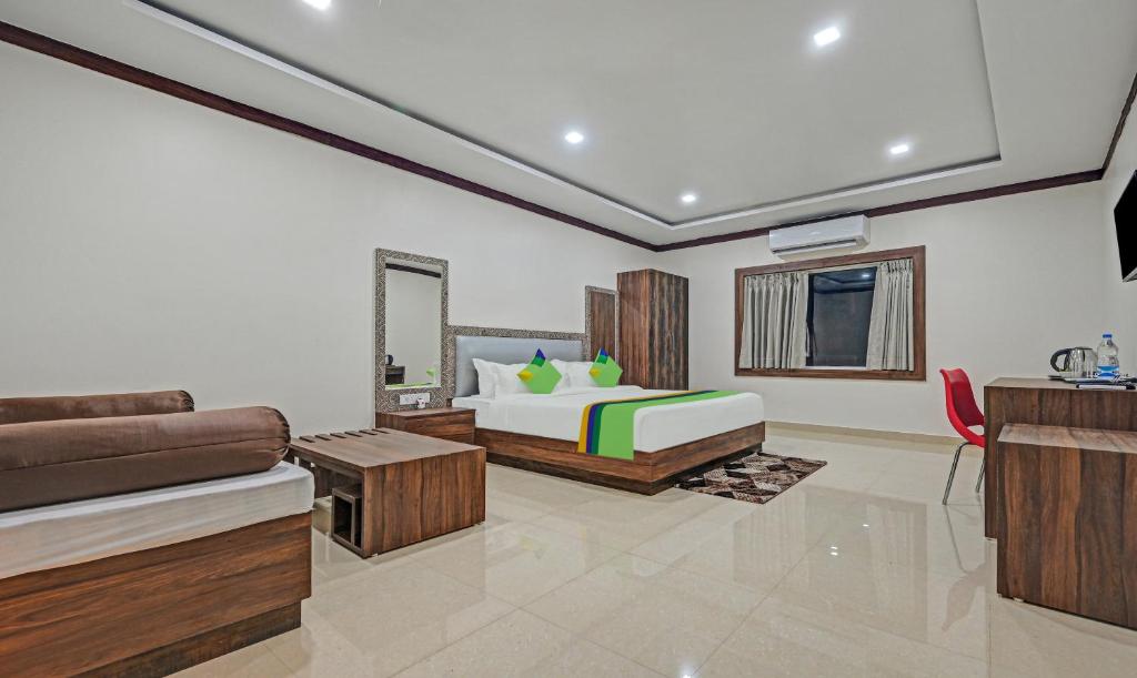a bedroom with a bed and a couch and a tv at Treebo Trend Paradise Premium Rasulgarh in Bhubaneshwar