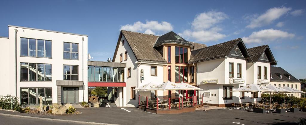 a large white building with umbrellas in a parking lot at Haus Hubertus in Winterspelt