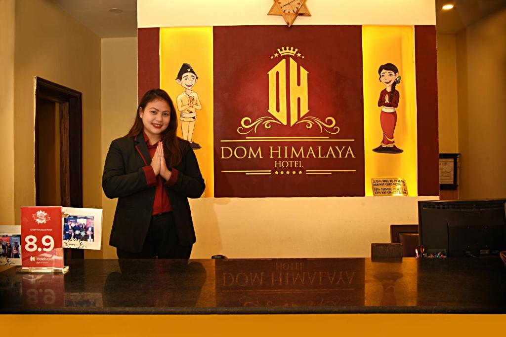 a woman standing behind a counter in front of a sign at DOM Himalaya Hotel in Kathmandu