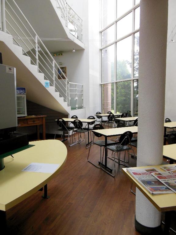 an empty classroom with tables and chairs and stairs at Mister Bed Chambray Les Tours in Chambray-lès-Tours