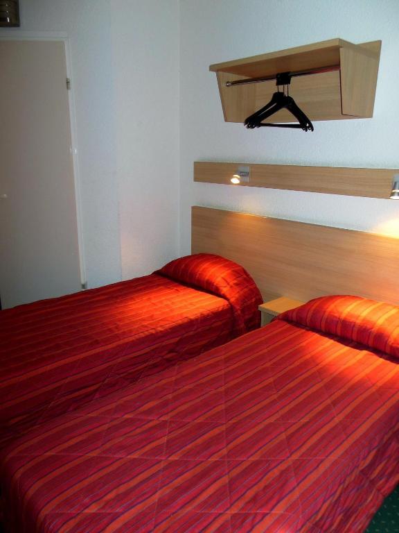 two beds in a hotel room with red sheets at Mister Bed Chambray Les Tours in Chambray-lès-Tours