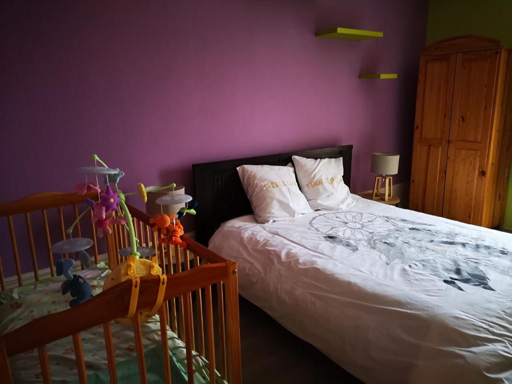 een slaapkamer met een bed en een paarse muur bij Maison familiale de l Abbaye in Clairvaux