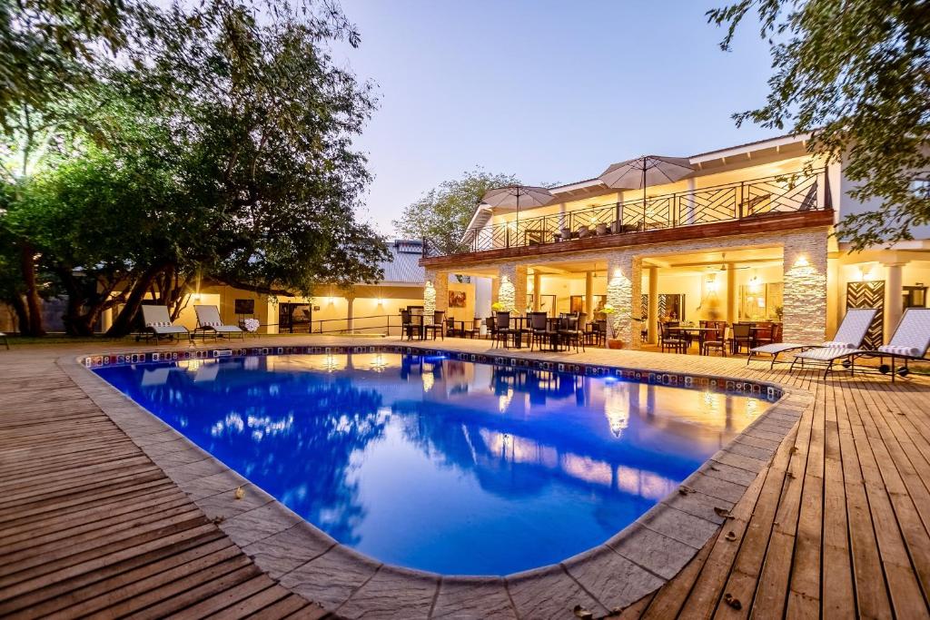 a swimming pool in front of a house at Nkosi Guest Lodge in Victoria Falls