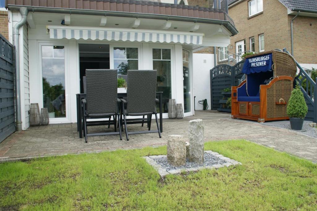 a patio with chairs and a table in a yard at Ferienwohnung Flensfjord in Wees