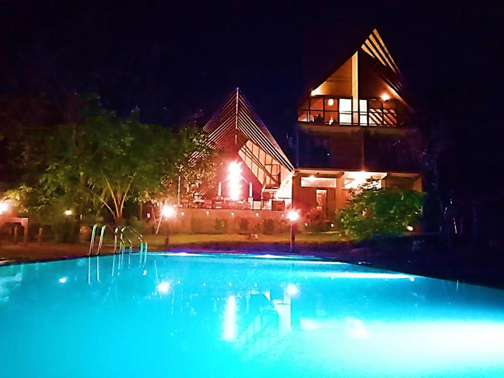 ein Schwimmbad in der Nacht mit einem Gebäude im Hintergrund in der Unterkunft Go Go Green Resort in Habarana