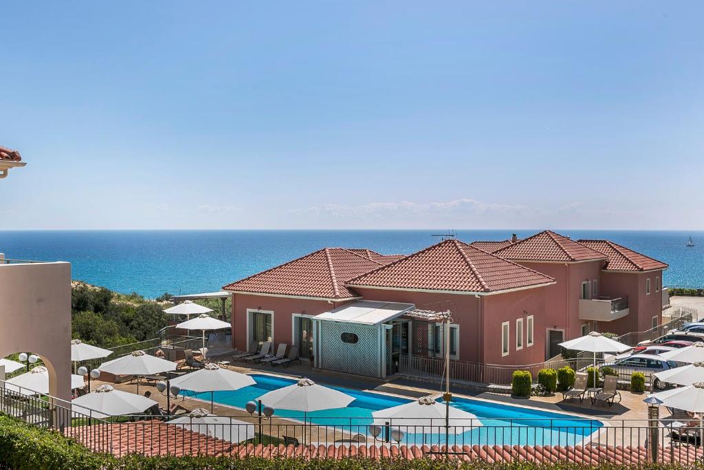 a resort with a pool and umbrellas and the ocean at Crystal Palace - Vista in Skala