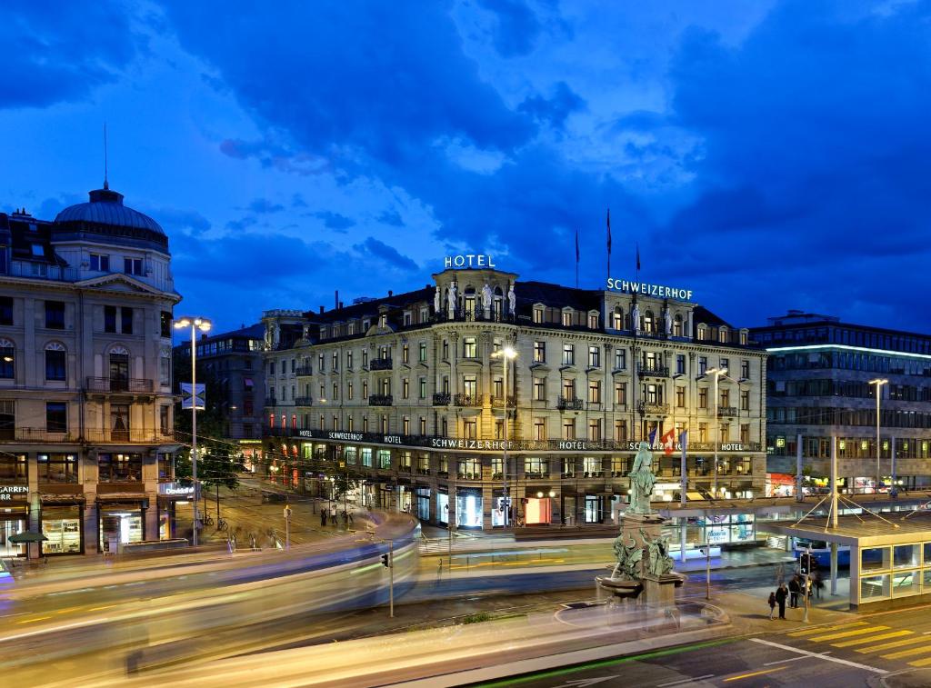 a city with a building and a street at night at Hotel Schweizerhof Zürich in Zurich