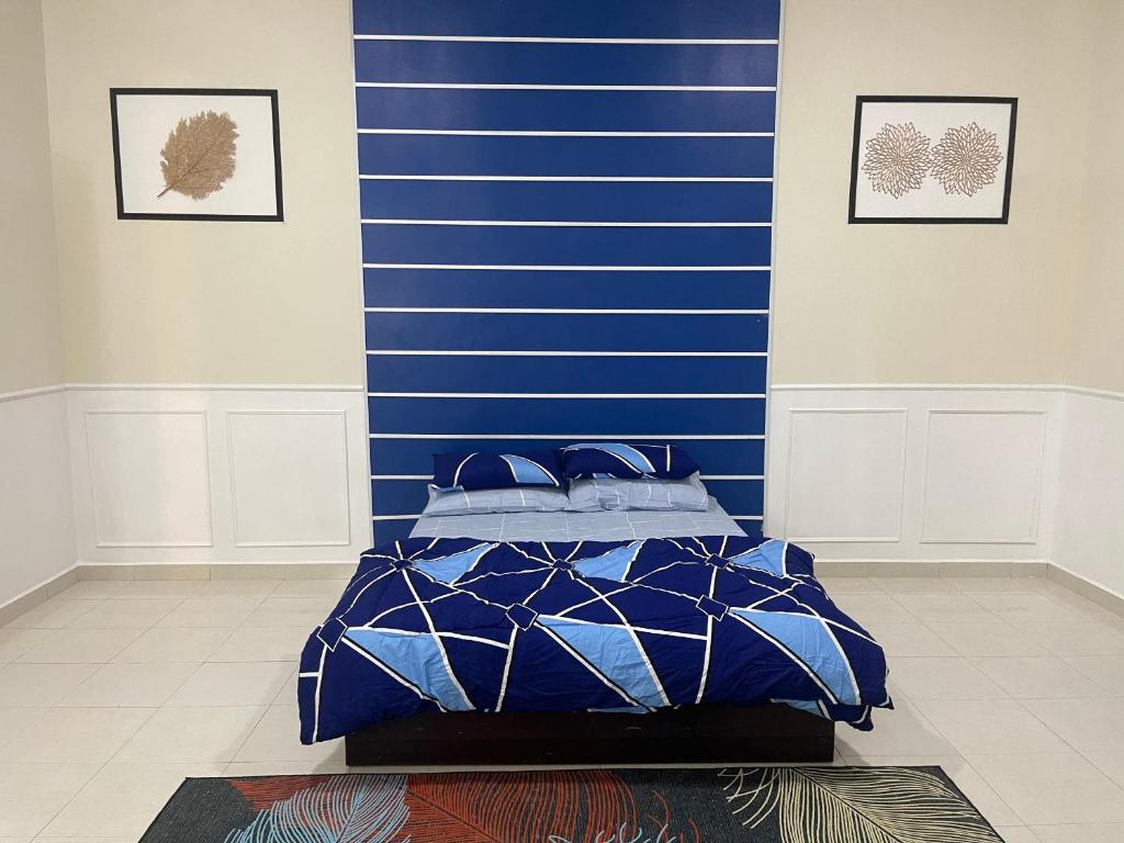 Cama en habitación con pared azul en No 61 Nazirin Homestay Tmn Indah Raya 2 Manjung Lumut, en Lumut