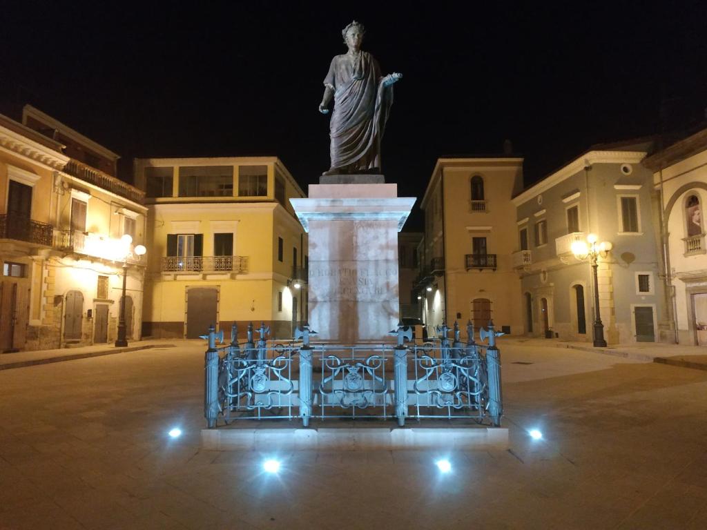 Bed and Breakfast In Piazza Orazio في فينوسا: تمثال في منتصف الشارع في الليل