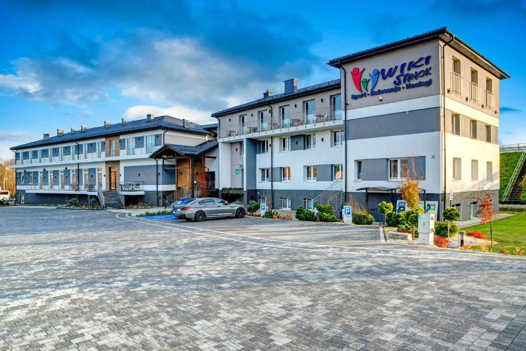 een gebouw met een auto geparkeerd op een parkeerplaats bij Hotel Wiki Sanok Events & Bowling in Sanok