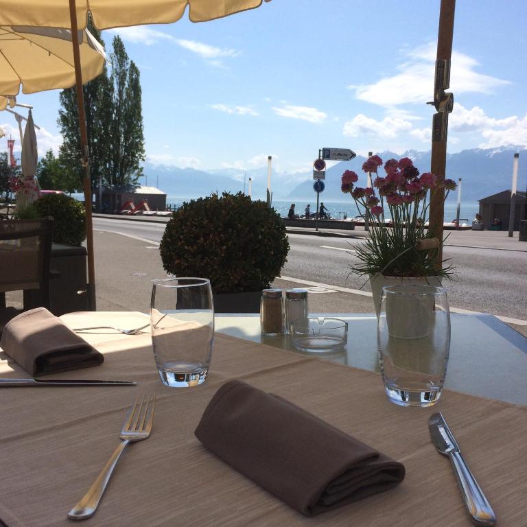a table with glasses and napkins on a table with a view at Hôtel du Port in Lausanne