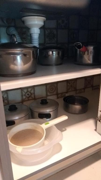a kitchen with pots and pans on a shelf at Bangalô no alto da colina no Villas do Pratagy - Maceió in Maceió