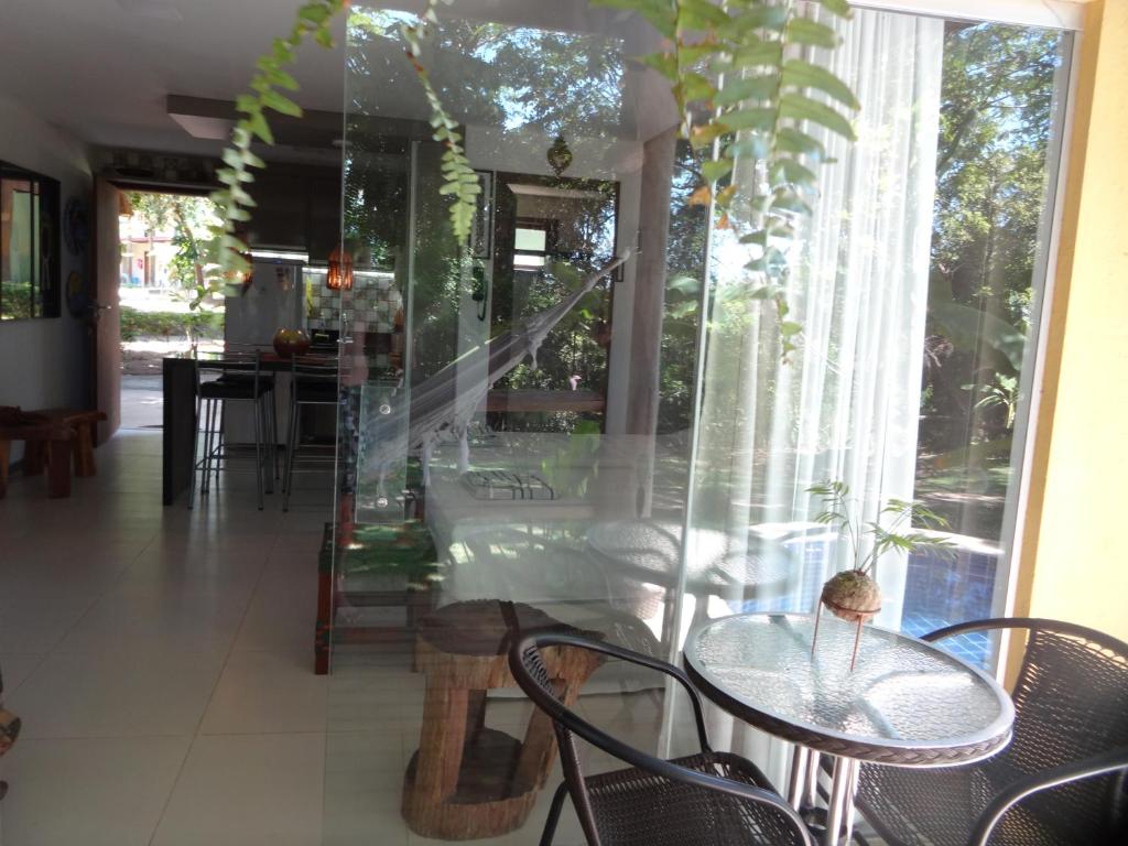 a dining room with tables and chairs and a window at Bangalô no alto da colina no Villas do Pratagy - Maceió in Maceió