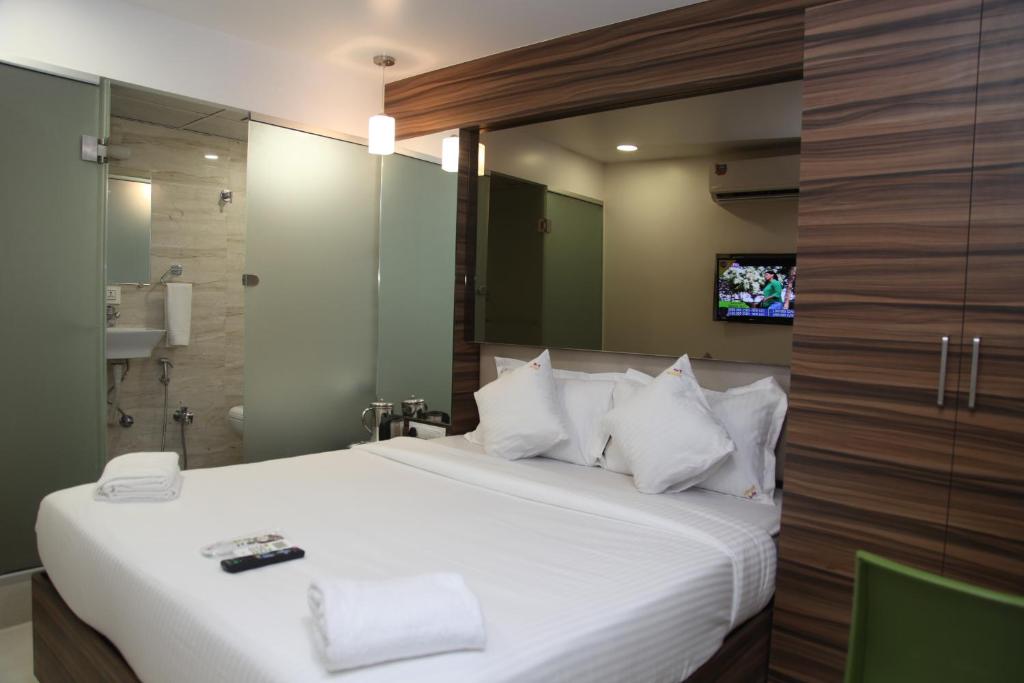 um quarto com uma grande cama branca e uma televisão em Hotel Lucky Galaxy em Mumbai