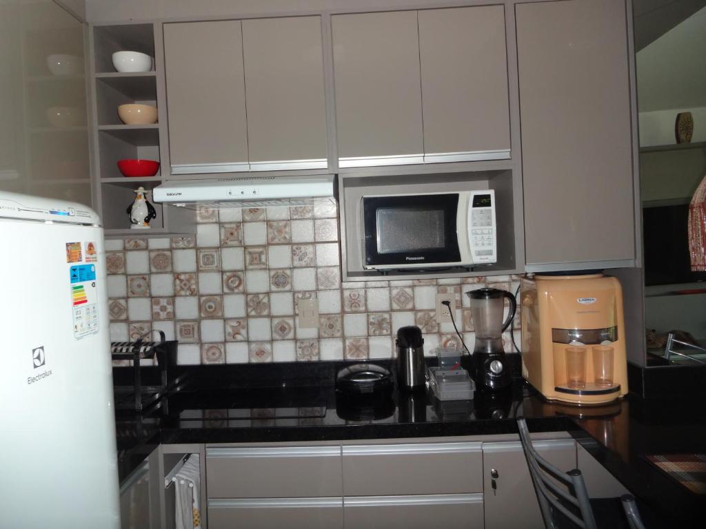 a kitchen with white cabinets and a microwave at Bangalô no alto da colina no Villas do Pratagy - Maceió in Maceió