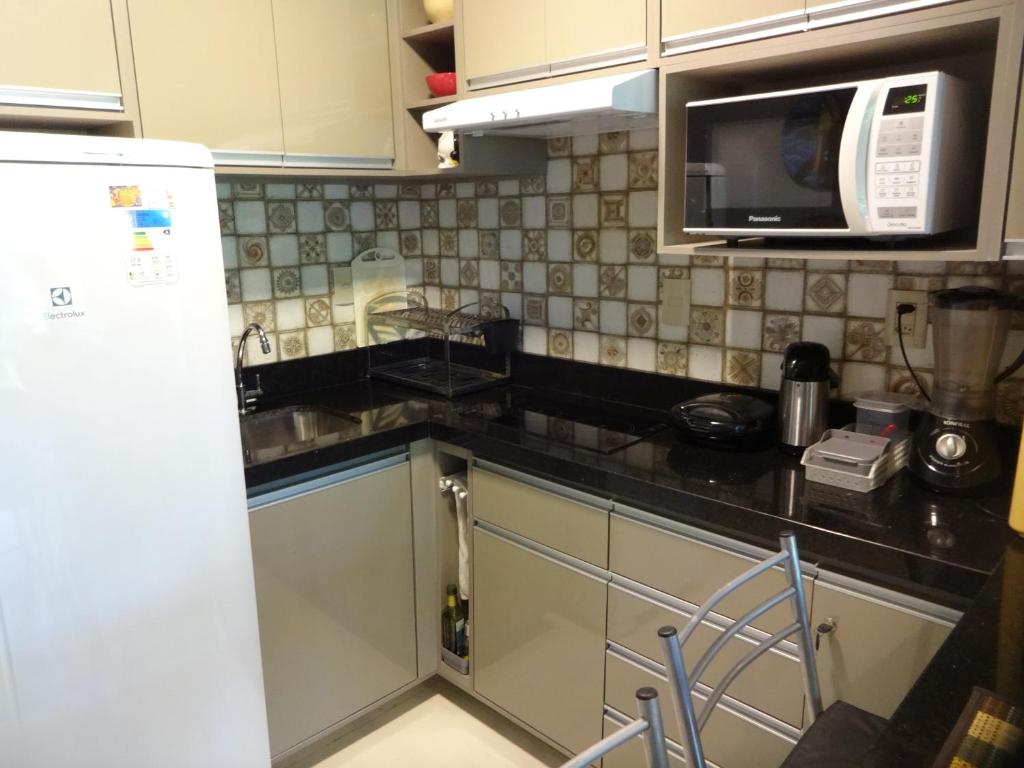 a kitchen with a white refrigerator and a microwave at Bangalô no alto da colina no Villas do Pratagy - Maceió in Maceió