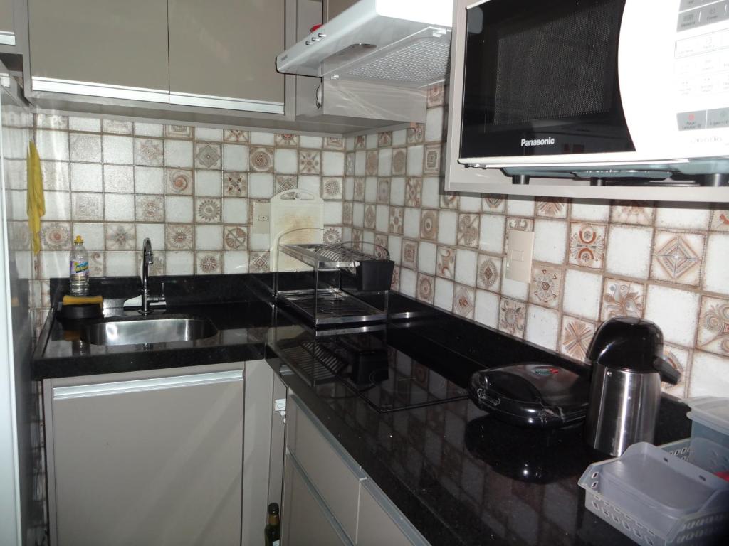 a kitchen with a sink and a microwave at Bangalô no alto da colina no Villas do Pratagy - Maceió in Maceió
