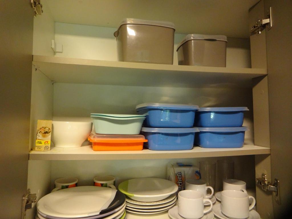 a kitchen pantry with bowls and plates on shelves at Bangalô no alto da colina no Villas do Pratagy - Maceió in Maceió