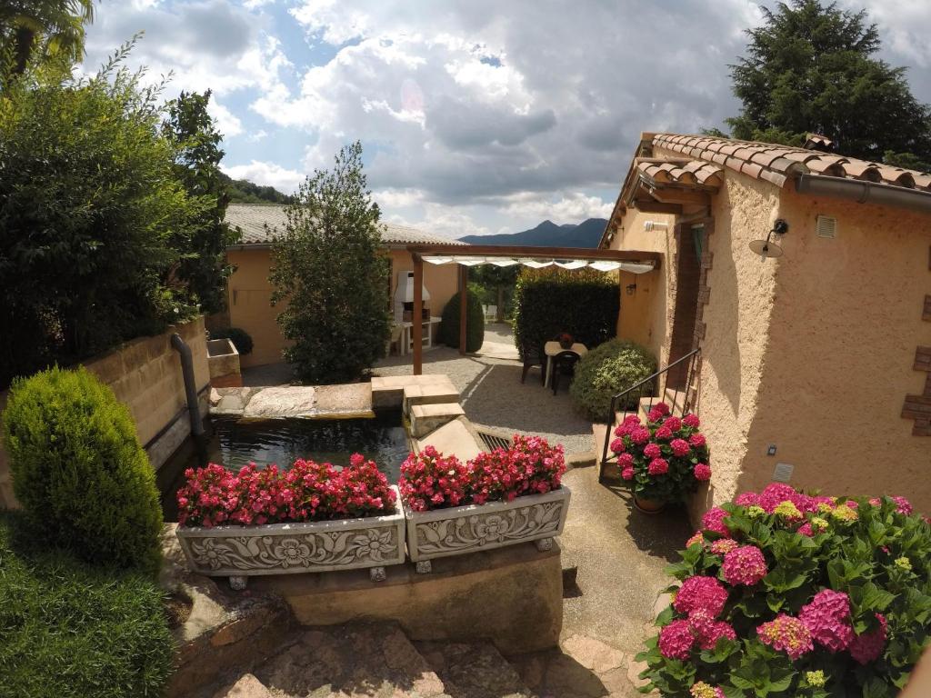 un jardín con una fuente y flores en un patio en Apartamento con jardín, barbacoa y piscina en pleno Montseny Mas Romeu Turisme Rural, en Arbúcies