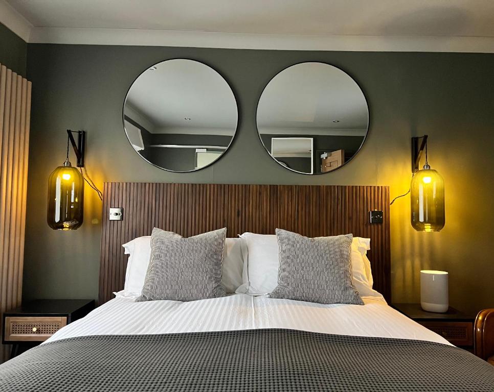 a bedroom with a large bed with two mirrors on the wall at Rockmount Rooms & Apartment in Tavistock