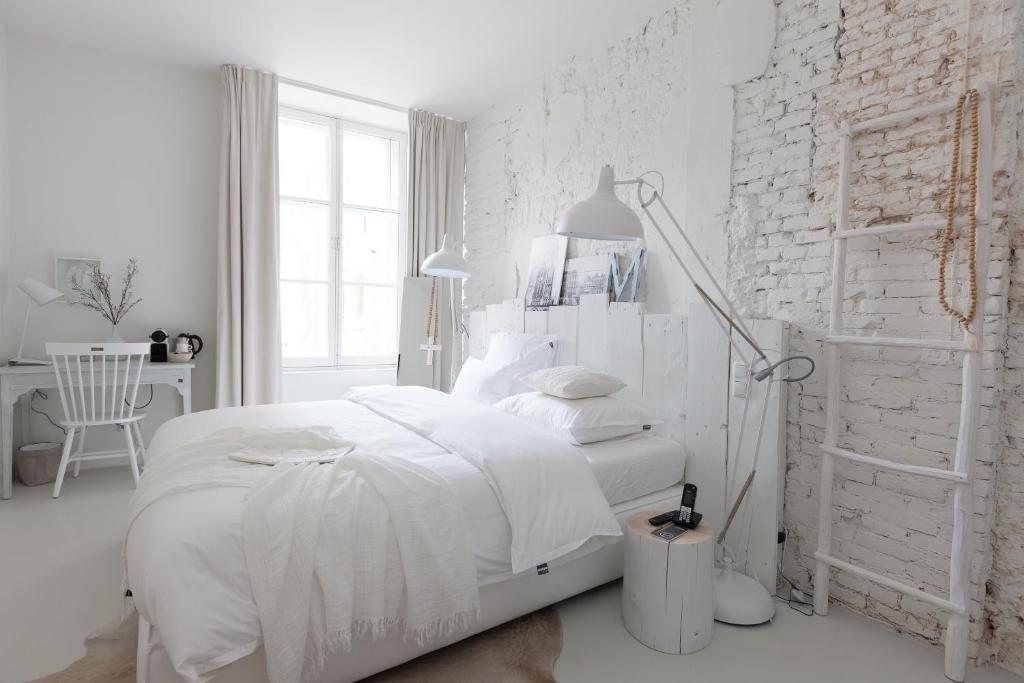 Dormitorio blanco con cama y pared de ladrillo blanco en Mother Goose Hotel en Utrecht