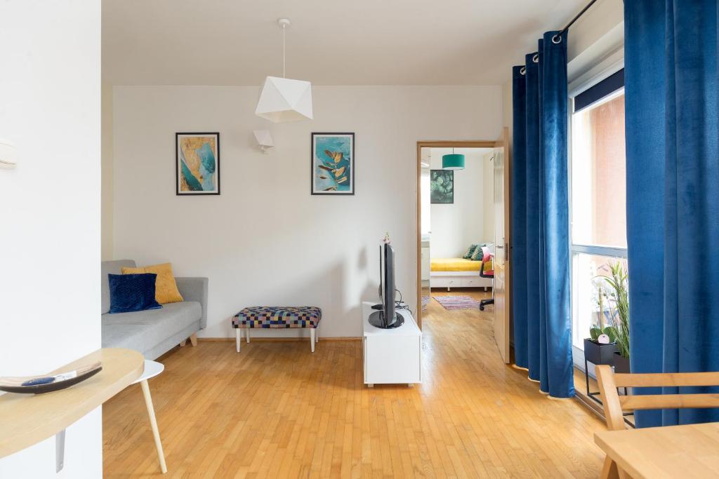 een woonkamer met een televisie en blauwe gordijnen bij Metro Młynów Pleasant Apartament in Warschau
