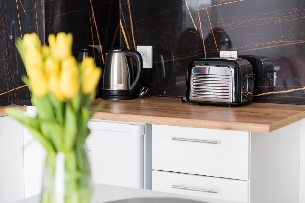 a counter with a microwave and a vase of yellow flowers at Apartament Hania in Gdańsk