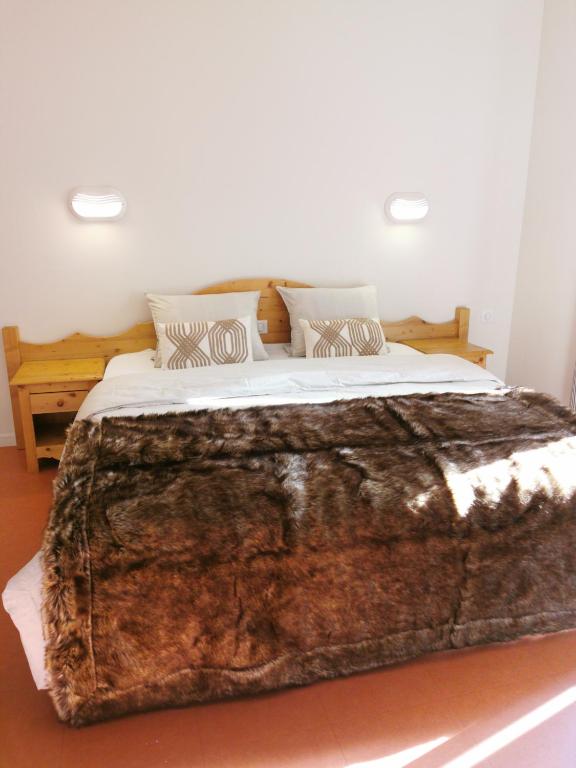 a bedroom with a large bed with a faux fur blanket at Auberge du Freney in Le Freney-dʼOisans