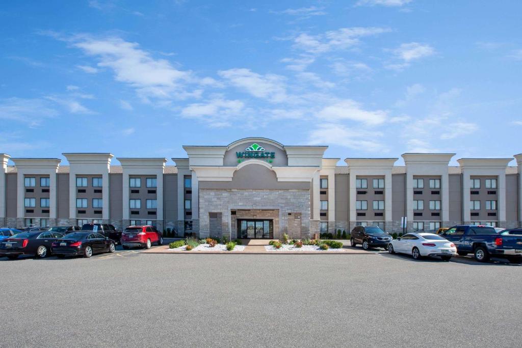 a large building with cars parked in a parking lot at Wingate by Wyndham Detroit Metro Airport in Romulus