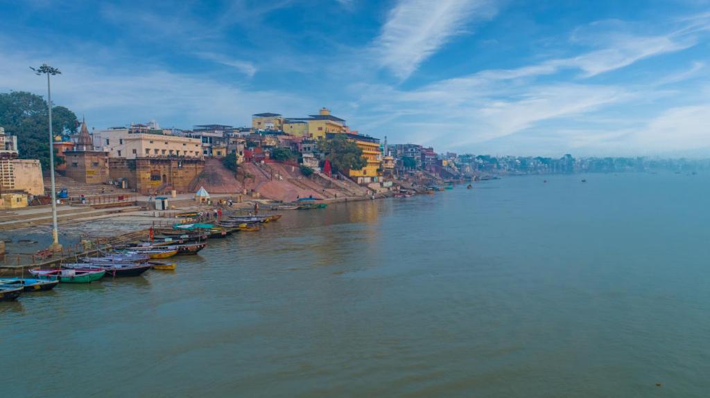 a river with boats parked on the shore of a city at Amritara Suryauday Haveli in Varanasi