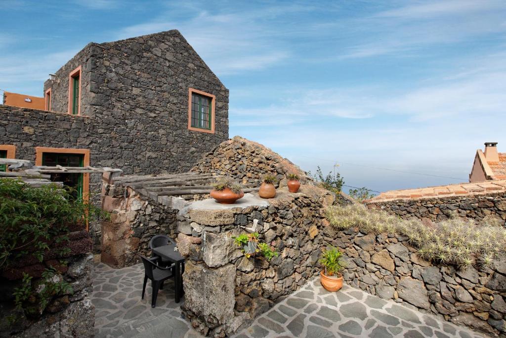 a stone house with a stone wall and some plants at Las Guindas in Valverde