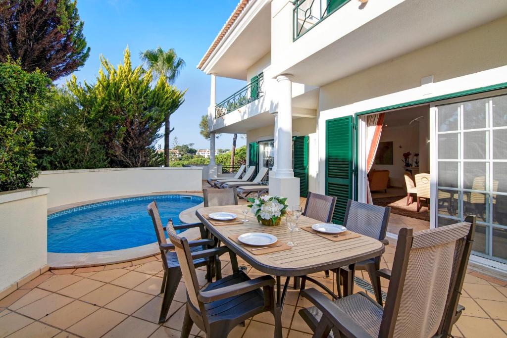 a patio with a table and chairs next to a swimming pool at Casa Valerie in Vale do Lobo