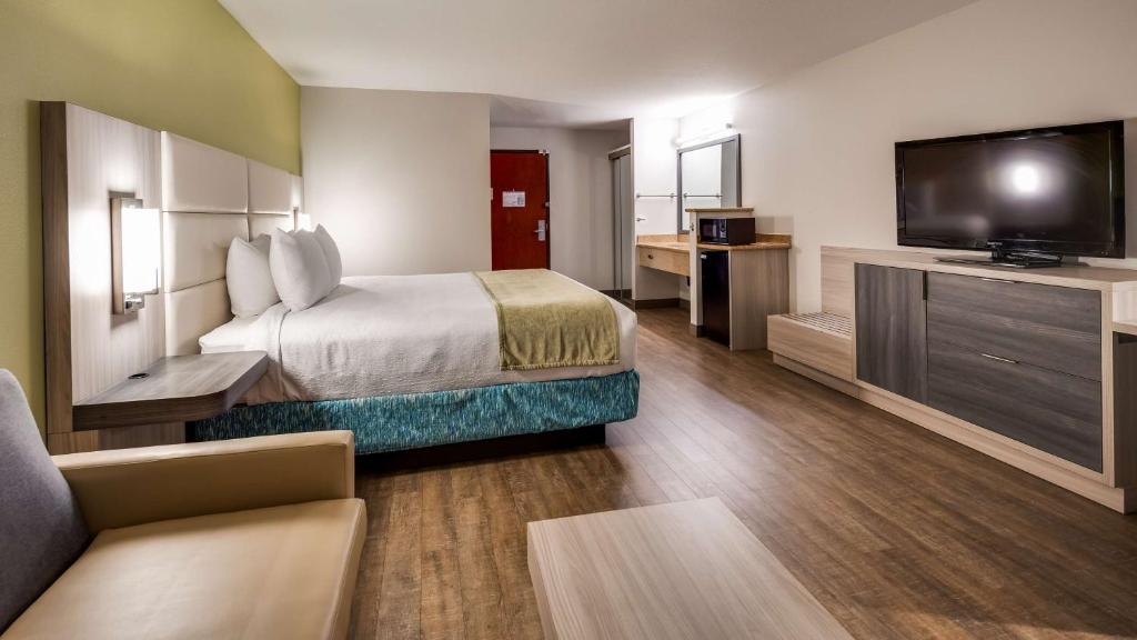 a hotel room with a bed and a flat screen tv at Best Western Sandy Inn in Sandy