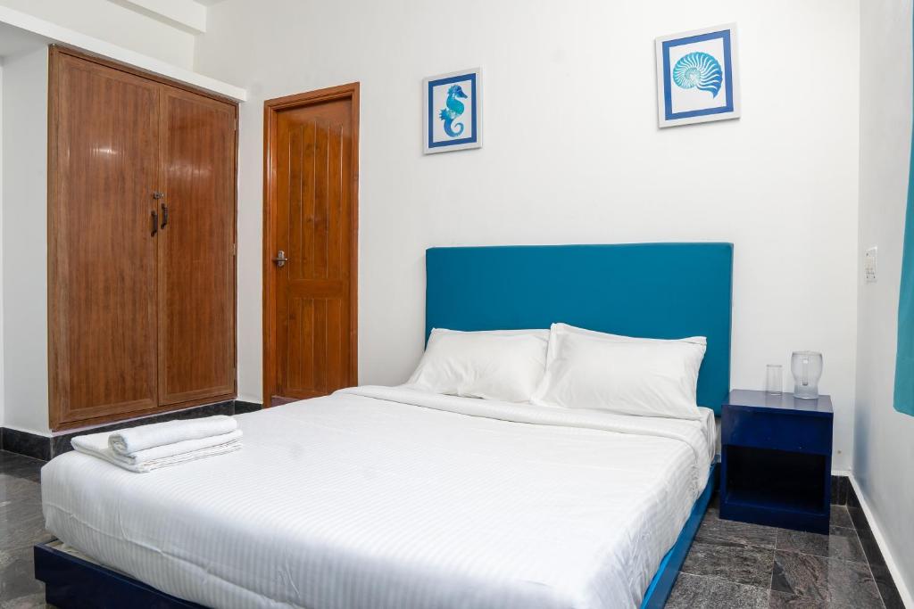 une chambre avec un grand lit et une tête de lit bleue dans l'établissement Deer Suites and Spa- Rock Beach White Town Zone , French Quarter, Pondicherry, à Pondichéry