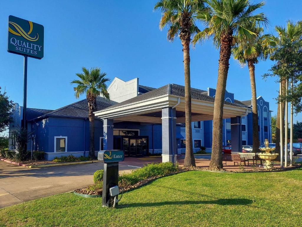 a sign in front of a hotel with palm trees at Quality Suites Houston NW Cy-Fair in Houston