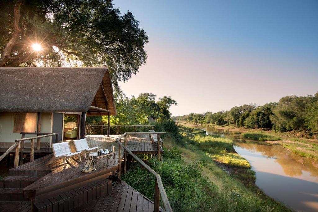 a house with a deck next to a river at Pafuri Camp in Makuleke Contract Park