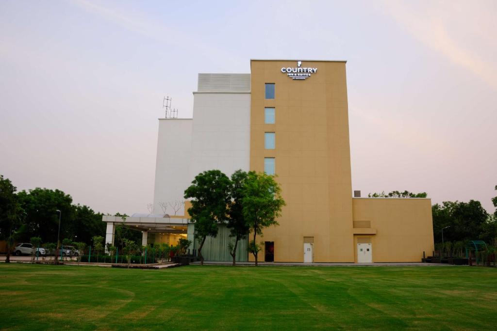 ein Gebäude mit einem Grasfeld davor in der Unterkunft Country Inn & Suites by Radisson, Gurugram Sohna Road in Sohna