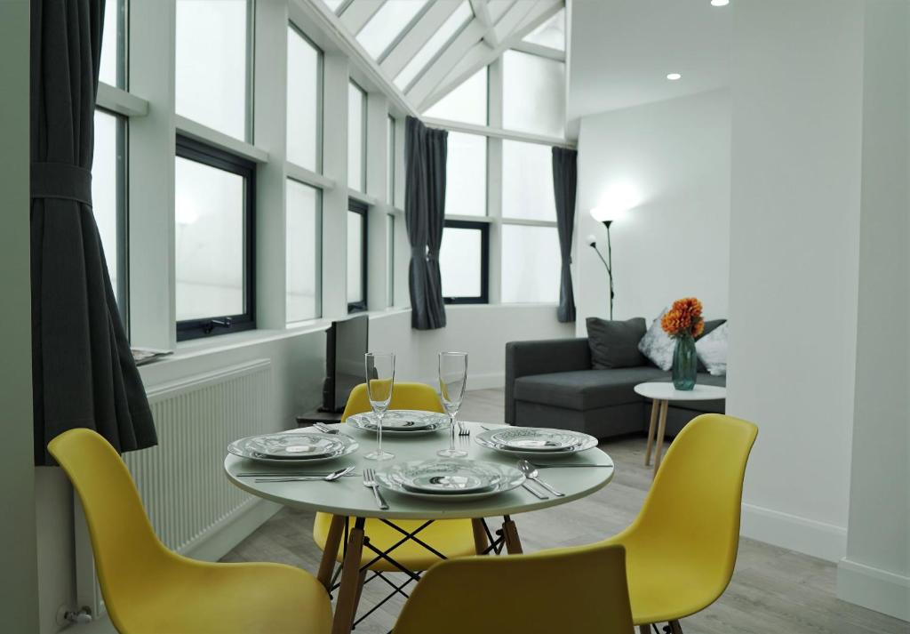a dining room with a table and yellow chairs at Sapphire House Apartments in Telford