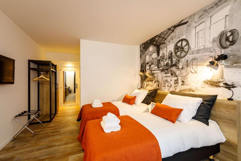 a bedroom with two beds with orange and white sheets at B-INN Lier in Lier