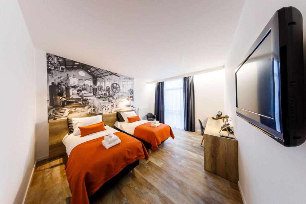 a bedroom with two beds and a flat screen tv at B-INN Lier in Lier