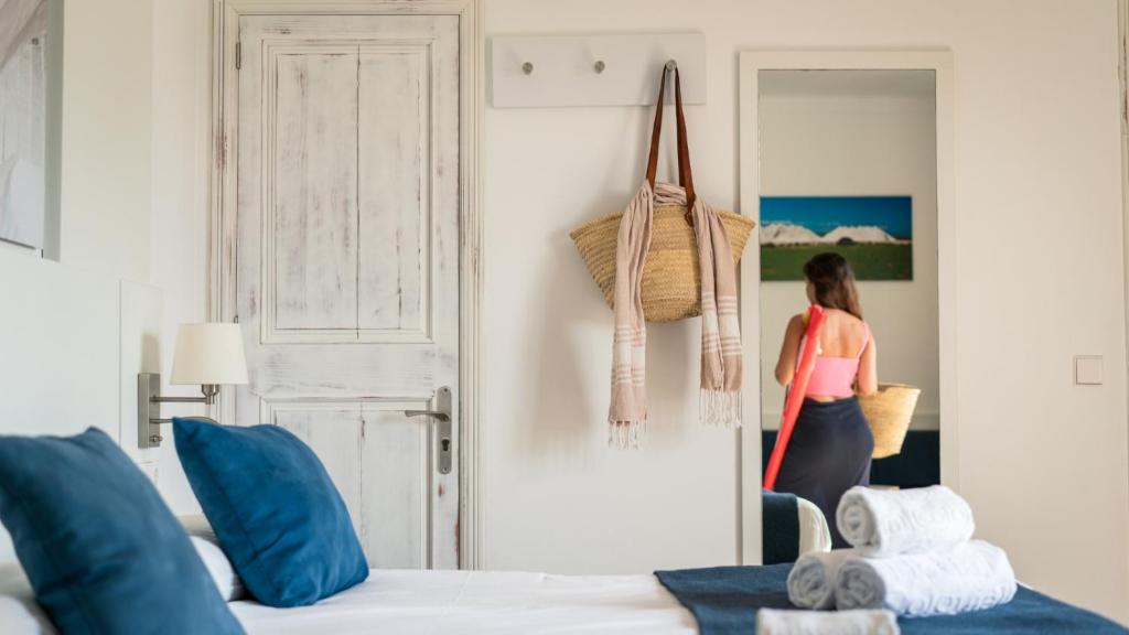 una mujer entrando en un dormitorio con una cama en Hotel Colonial en Colonia Sant Jordi