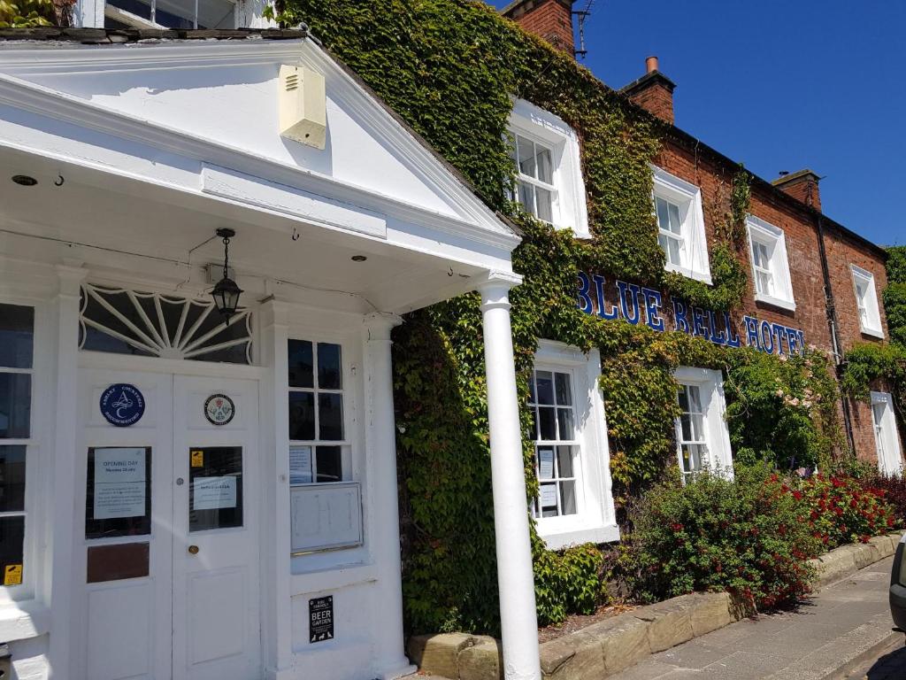 a white building with ivy on the side of it at Blue Bell Hotel in Belford