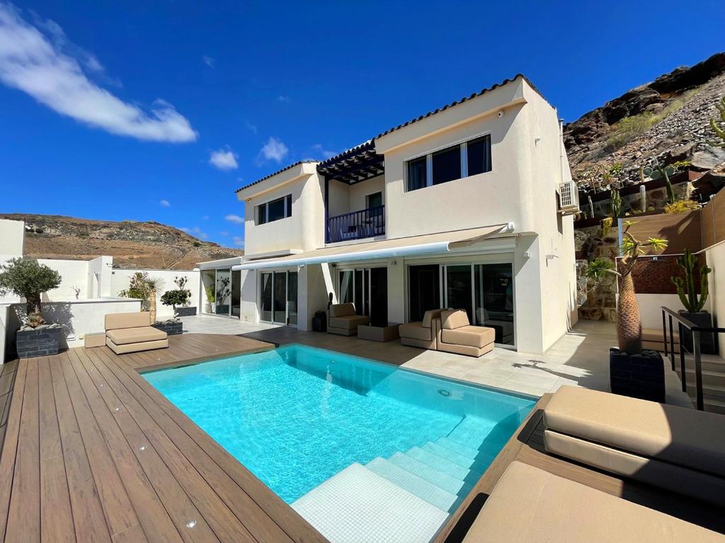a villa with a swimming pool in front of a house at Luxury Villa Morelli with seaview & heated pool in Maspalomas