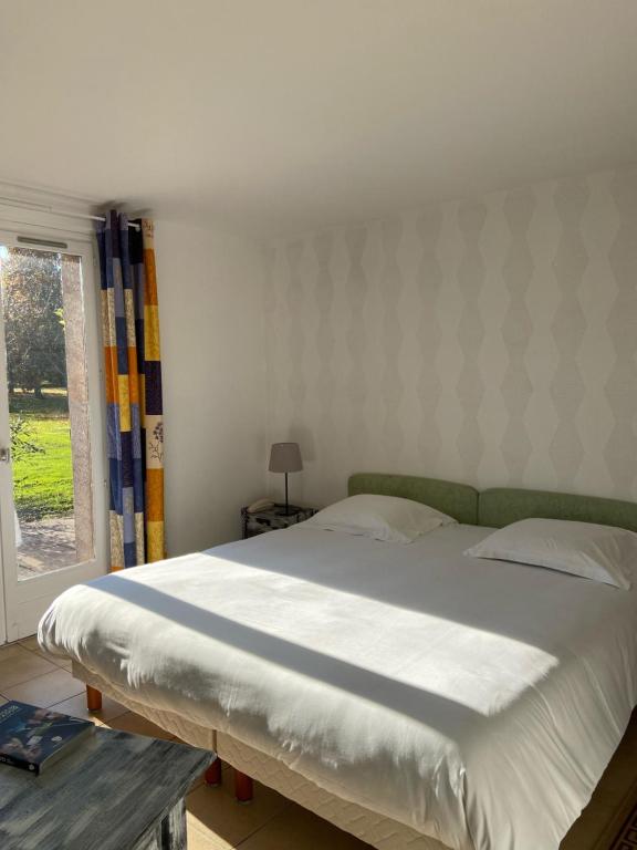 a large bed in a bedroom with a window at Golf Hotel de la Carte in Chouzy-sur-Cisse